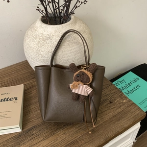Detailed close-up of dark brown bucket bag with lychee grain leather and bear charm