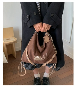 Detail of dark brown suede tote bag featuring all the best embroidery and cookie pendant