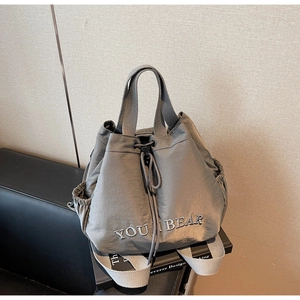 Detail of grey nylon drawstring backpack showing YOU I BEAR embroidery and side pocket
