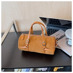 Detailed close-up of brown suede cylinder Boston bag with silver metal buckle and top handle