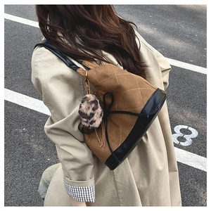 Detailed close-up of a caramel quilted bucket bag with leopard fur charm and bow detail