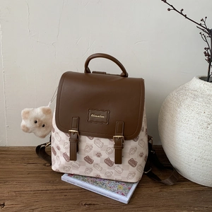 Détail d'un sac à dos imprimé chat avec rabat en cuir marron sur un banc en bois