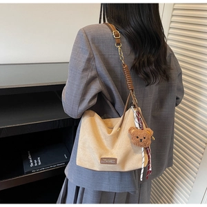 Détail du cabas en daim beige avec bordure en cuir marron et breloque ourson mignonne