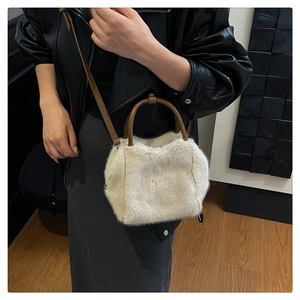 Detail of white faux fur texture and brown leather strap on a stylish plush crossbody bag