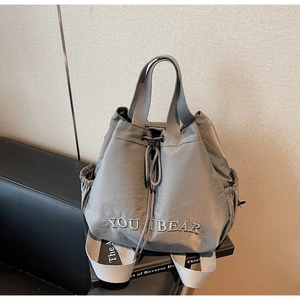 Detail view of grey nylon drawstring backpack with YOU I BEAR embroidery and side pockets