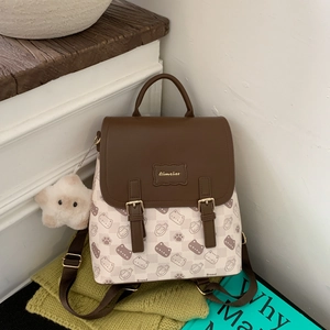 Détail d'un sac à dos en toile beige avec imprimé chat mignon et breloque en peluche