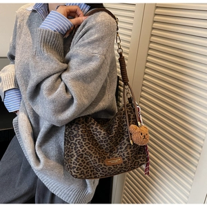 Detail of trendy leopard print tote bag with cute brown plush bear charm accessory