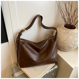 Detailed close-up of dark brown textured tote bag with golden buckle and wide strap