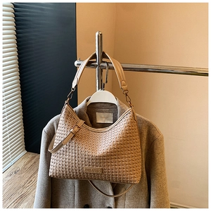 Detail of beige woven hobo bag with adjustable strap styled on a coat rack