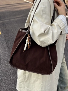 Retro faux suede leopard brown tote bag with beaded tassel charm on a beige trench coat