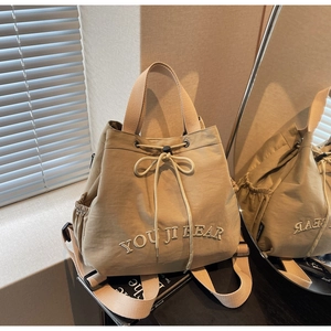 Macro detail of khaki canvas backpack with drawstring closure and bow decoration
