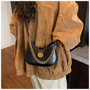 Détail du sac demi-lune noir avec bandoulière chaîne dorée et fermoir rotatif chic
