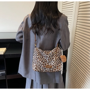 Detail view of leopard print tote bag with brown straps and cute teddy bear charm