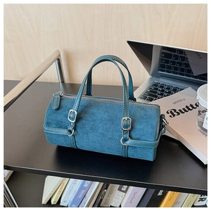 Detailed macro shot of blue cylindrical handbag with matte finish and silver hardware