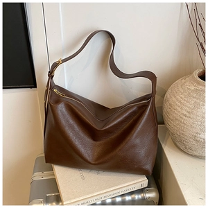 Detailed close-up of dark brown soft leather hobo bag with gold hardware and wide strap