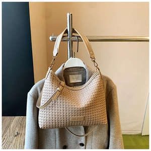 Detailed view of beige woven texture handbag with adjustable leather shoulder strap