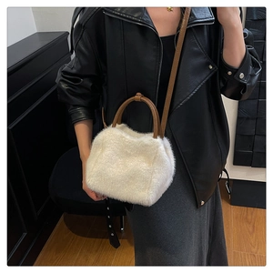 White faux fur handbag with brown leather handles worn by a model with a black leather jacket