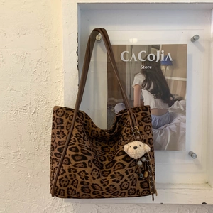 Detail view of leopard print tote bag with brown straps and cute bear plush charm