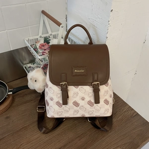 Détail d'un sac à dos en toile beige à motifs chat, rabat en cuir et breloque en peluche