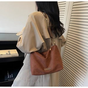 Détail du sac cabas en suède avec bandoulière en chaîne de cuir tressé et finitions dorées