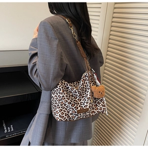 Detail of leopard print tote bag with brown leather strap and plush bear charm