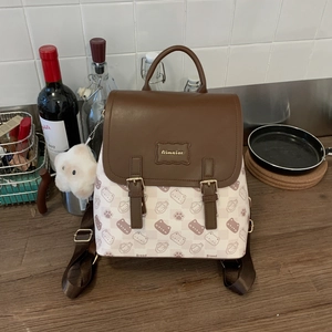 Détail du sac à dos chat mignon avec rabat en cuir marron et pendentif peluche sur table