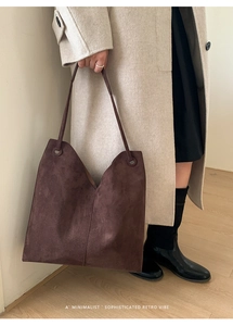 Detail einer großen braunen Wildleder-Tragetasche mit V-Ausschnitt an einem Model-Outfit