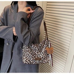 Detail of trendy leopard print shoulder bag with brown straps and cute bear charm
