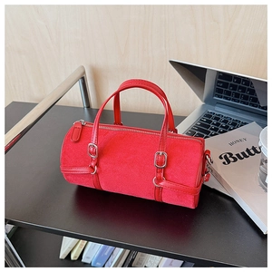 Detail of red cylindrical handbag with suede texture, silver buckles and office props