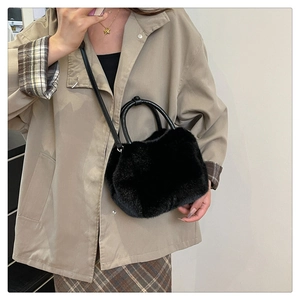 Mirror selfie showing black faux fur crossbody bag with round hard handles and strap