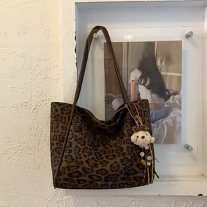 Detail of leopard print tote bag with plush bear charm and colorful beaded keychain accessory