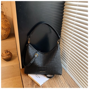 Detailed view of black woven texture hobo bag with gold buckle and brand logo plate