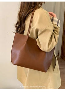 Side view of dark brown litchi grain leather tote bag worn by a model in a beige trench coat