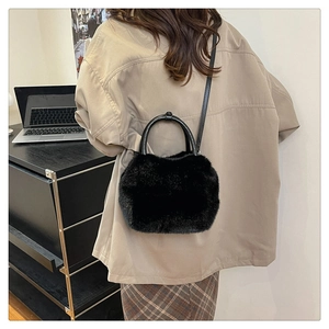 Detail of black faux fur crossbody bag with round handle shown in a daily lifestyle setting