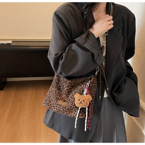 Detail of leopard print tote bag with plush bear charm and leather strap detail