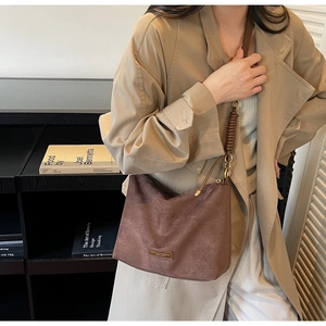 Détails du sac fourre-tout en daim marron avec plaque de marque et bandoulière tressée