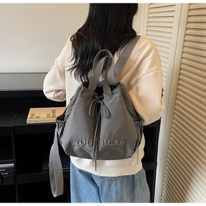 Detailed view of grey drawstring backpack with YOU I BEAR embroidery in a minimalist setting