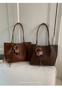 Detailed view of caramel leather tote bag with a cute bear charm and pebbled texture
