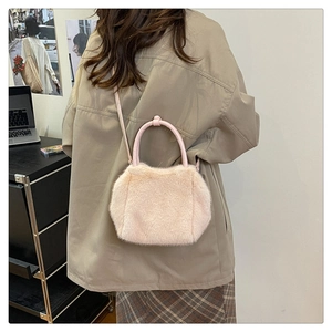 Detailed close-up of pink faux fur crossbody bag with leather handles and strap