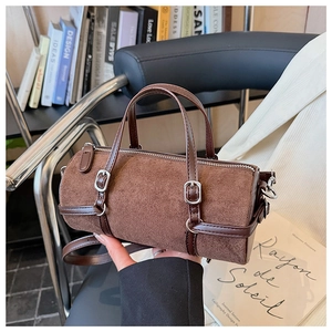 Close-up of brown suede barrel bag with smooth leather trim and silver metal hardware