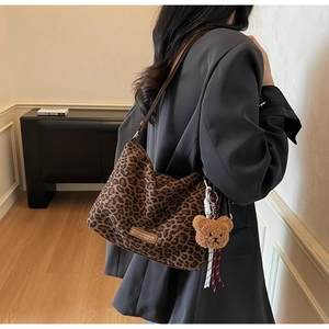 Detail of trendy leopard print tote bag with plush bear charm and fashion leather tag