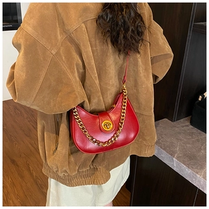 Détail d'un sac demi-lune rouge avec fermoir doré et bandoulière en chaîne métallique