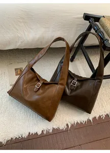 Close-up of matte PU leather tote bags in caramel and dark brown with metal buckles