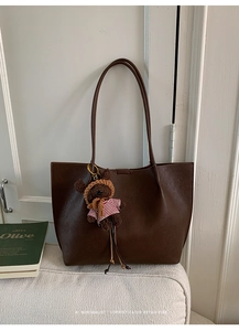 Detail of dark brown tote bag with premium pebble leather texture and cute bear charm