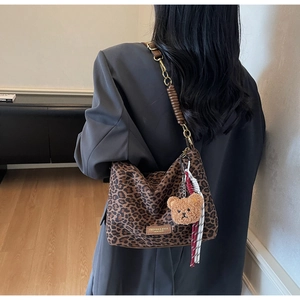 Detail of trendy leopard print tote bag with metal chain strap and cute bear charm