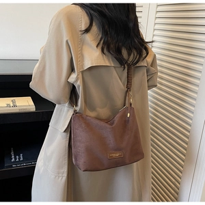 Détail d'un sac cabas en daim marron avec bandoulières tissées et écusson logo