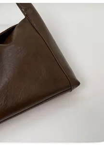 Detailed close-up of dark brown crescent bag showing fine stitching and oily leather texture