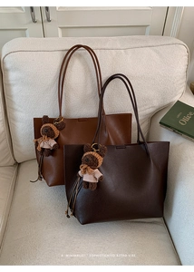 Detail of plaid tote bags with leather texture and cute bear charm on a cozy sofa