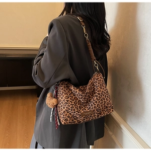 Detail of leopard print hobo bag with chain strap and bear charm worn by a model