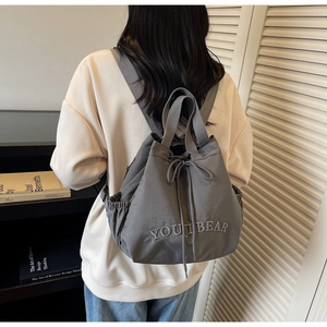 Detail view of grey drawstring backpack with YOUJI BEAR embroidery on satin nylon fabric